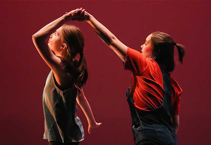 在舞蹈表演中，一个学生在舞台上旋转另一个学生