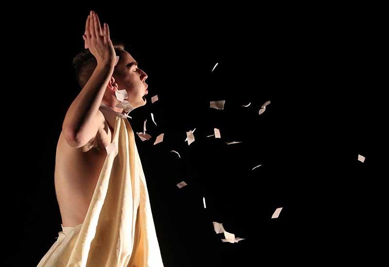 一名穿着长袍的表演者在舞蹈表演中向空中吹纸片