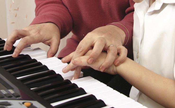 教年轻人弹钢琴的妇女