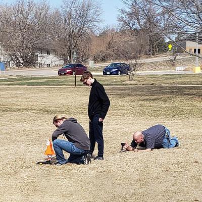 一个团队准备发射火箭，而一个人躺在地上安装摄像机