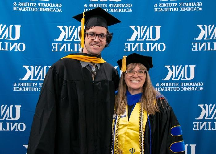 教授和毕业生戴着学士帽和学士服摆姿势.